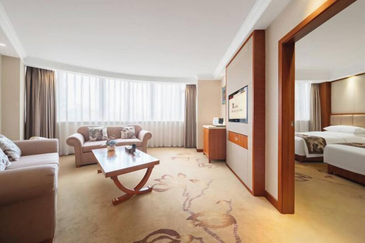 A hotel room with a sofa, a coffee table, a bed, and a desk.