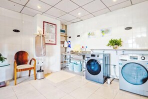 A laundry room with a washing machine, dryer, and ironing station. - Chengdu Eight Treasures Hotel(Kuanzhai Alley Luomashi Subway Station) (Chengdu)