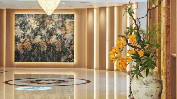 Eine moderne Lobby mit einem spiegelnden Boden, einem großen abstrakten Gemälde und einer Vase mit gelben Blumen.