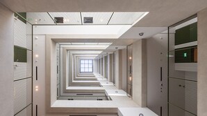 A modern, linear hallway with a central skylight and mirrored walls, creating a sense of depth. - Mood 22 - Deluxe Loft Studio: Chic & Cozy Retreat (Jumeirah Garden City)