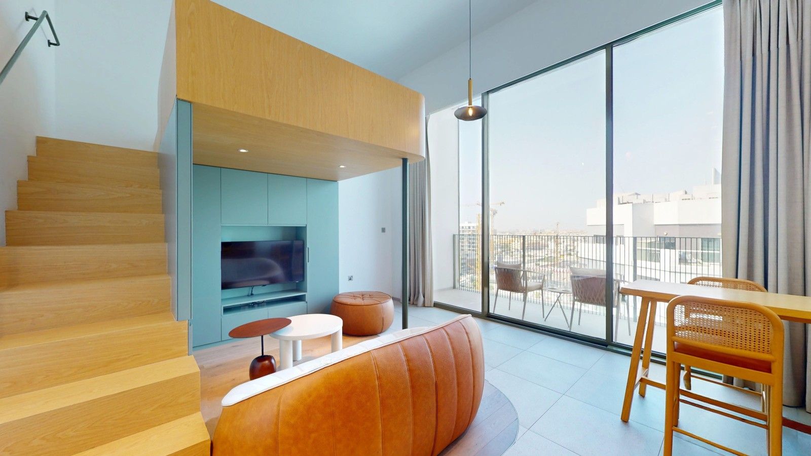 A modern living room with a sofa, a television, a dining area with chairs, and a staircase.
