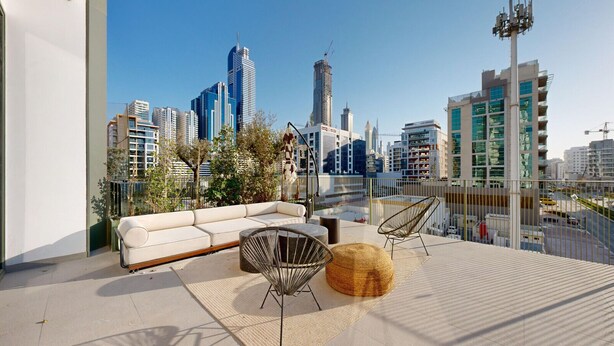 Una terraza en la azotea con sofá, sillas y vistas del horizonte urbano.