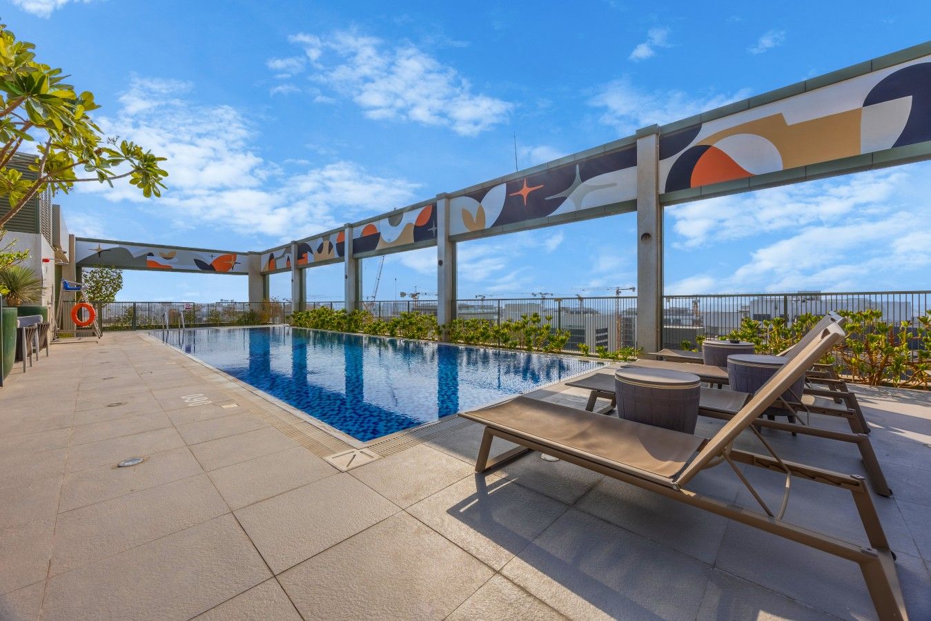 A rooftop pool area with lounge chairs and a view of the city skyline.