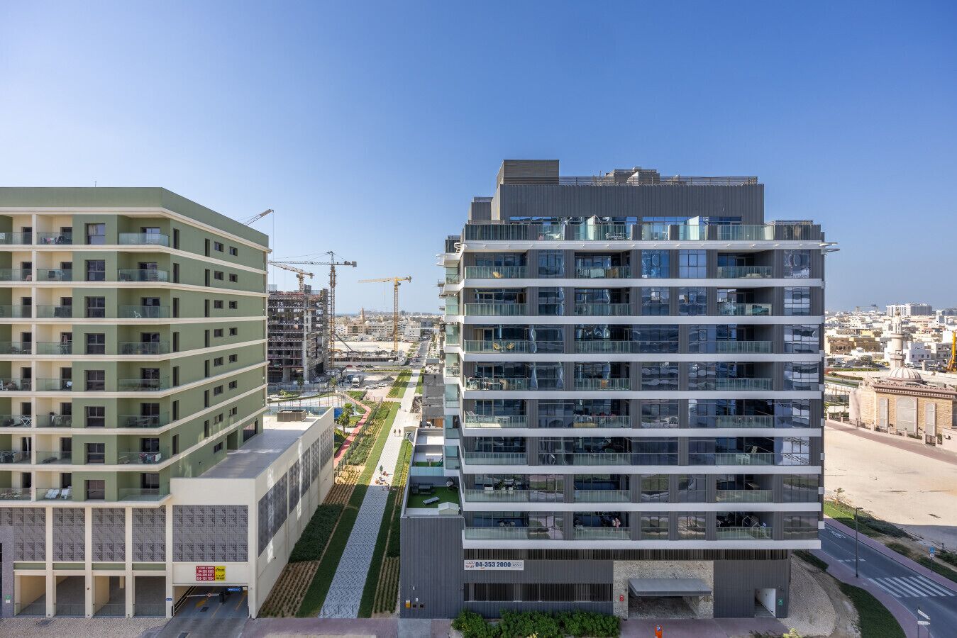Un immeuble moderne de grande hauteur, doté de nombreux balcons et d’un jardin sur le toit.