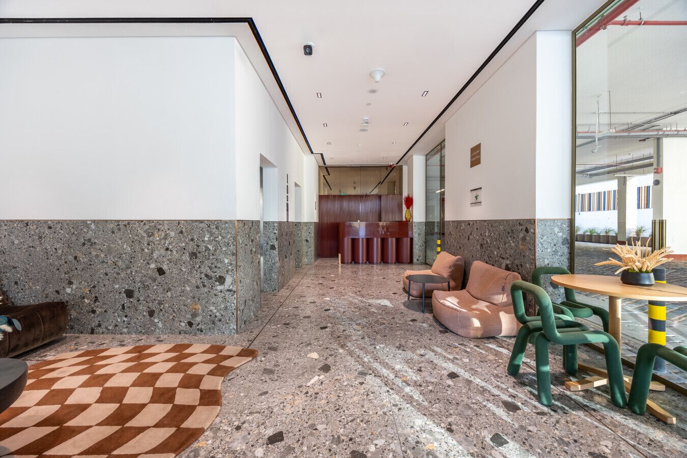 A modern lobby with a checkered carpet, seating area, and a reception desk.