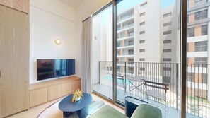 A modern apartment with a balcony, a flat-screen TV, and a small table with a vase. - Mood 45 - Deluxe Studio: Your Perfect Getaway (Jumeirah Garden City)
