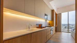 A modern kitchen with a large island, a built-in oven, and a view of the city through large windows.