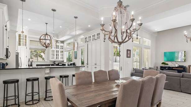 Una cocina amplia con armarios blancos, una mesa de comedor de madera y taburetes de bar.