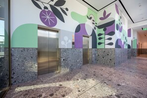A modern elevator area with a terrazzo floor and a colorful abstract mural on the walls. - Mood 45 - Two Bed: Elegant & luxurious (Jumeirah Garden City)