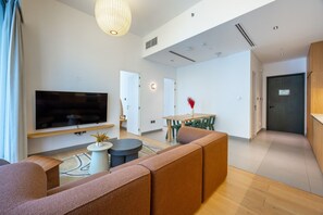 Un salon moderne comprenant un téléviseur à écran plat, un canapé, une table à manger avec des chaises et un vase décoratif.