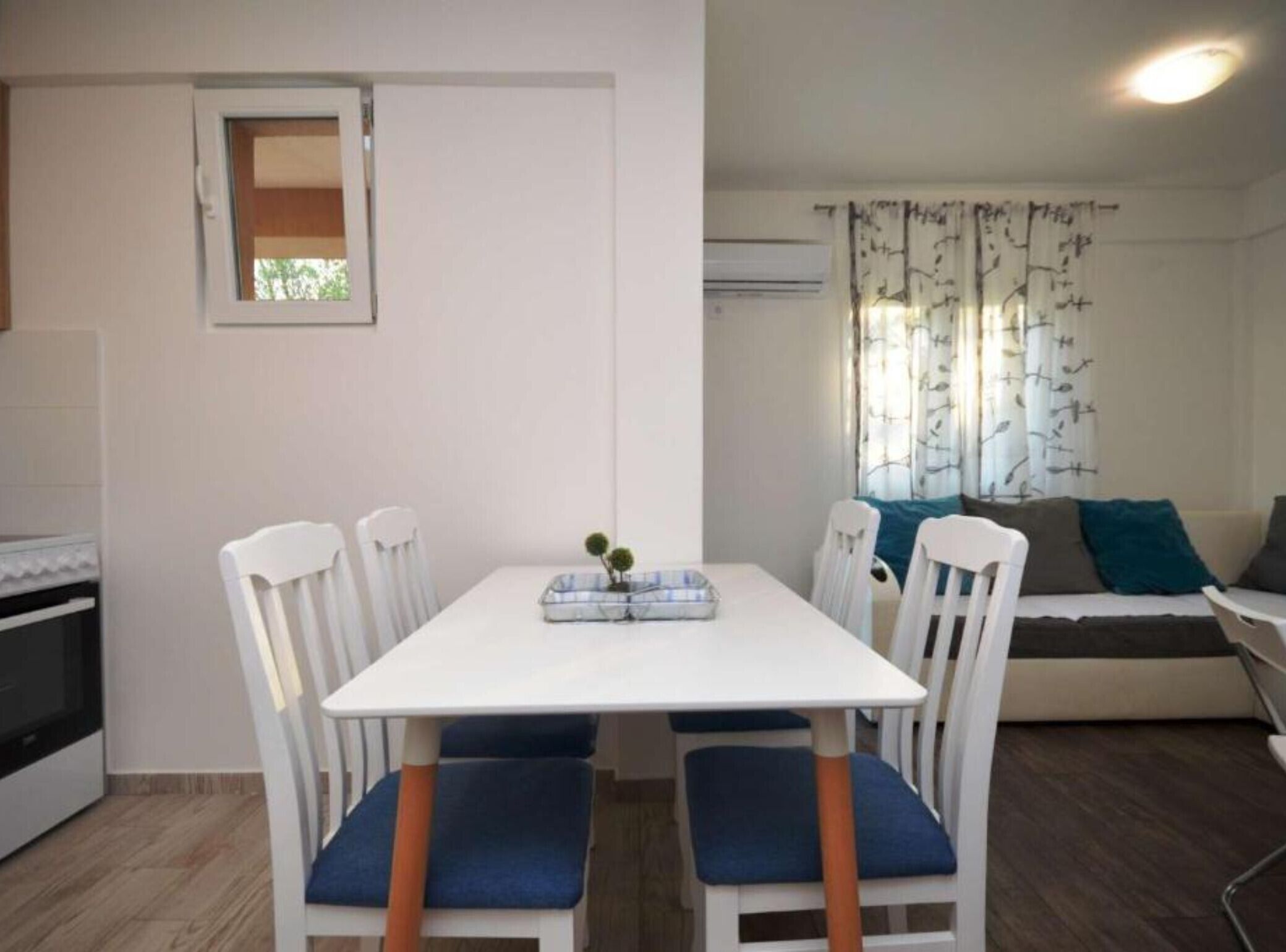 A compact living space with a dining table and chairs, a sofa, and a small kitchenette.