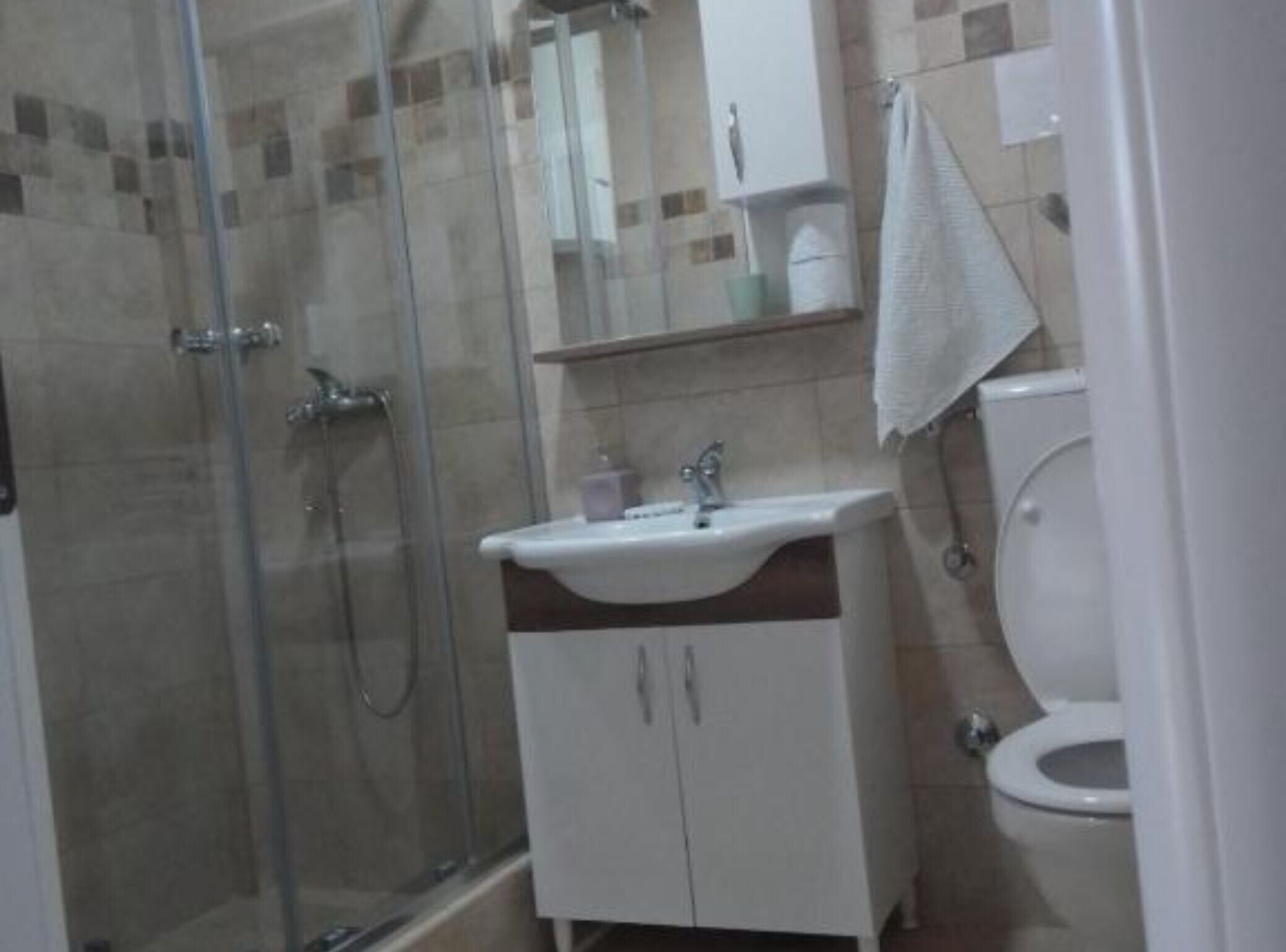 Un baño con cabina de ducha de vidrio, un lavabo con espejo y un inodoro.