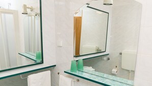 A modern bathroom with a glass vanity, a large mirror, a white sink, and a shower area. - Apartments Alba - Studio apartment (Rovinj)
