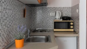 Una cocina compacta con microondas, estufa y pileta.