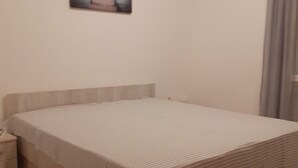 Una cama bien tendida con una colcha a rayas, una mesita de noche y un cuadro colgado en la pared.