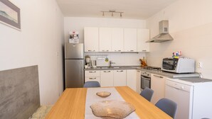 A compact kitchen with white cabinets, a stainless steel refrigerator, a microwave, and a gas stove.