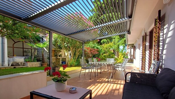 A covered patio area with a table, chairs, and a sofa.
