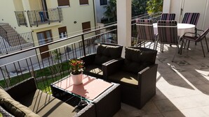 A balcony with wicker furniture, a small table, and a potted plant. - Apartments Alba - Three Bedroom Apartment (Rovinj)