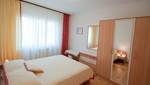 A bedroom with a bed, a bedside table, a wardrobe, and a mirror. - Apartments Alba - Three Bedroom Apartment (Rovinj)