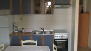 A compact kitchen with a table and chairs, a coffee maker, a sink, and a stove. - Apartments Alba - Three Bedroom Apartment (Rovinj)