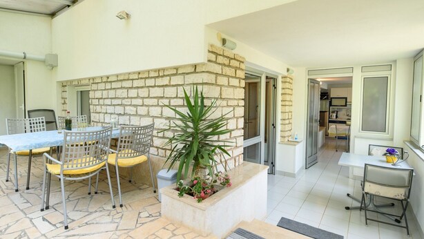 A patio area with a table and chairs, a potted plant, and a stone-tiled floor. - Apartments Alba - Two Bedroom apartment (Rovinj)