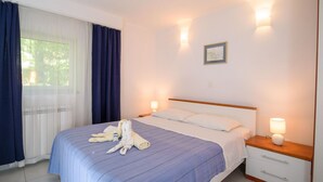 Een hotelkamer met een bed, twee bedlampen, een raam met gordijnen en een klein schilderij aan de muur.