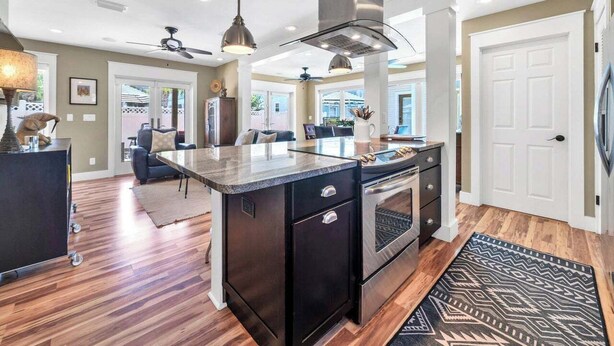 A spacious kitchen with a central island, dark cabinetry, stainless steel appliances, and pendant lighting.