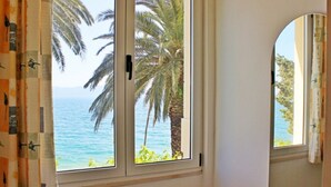 Ein Zimmer mit Blick auf einen Strand und Palmen.