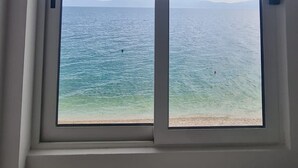 Una habitación con un ventanal grande con vistas a la playa y al mar.