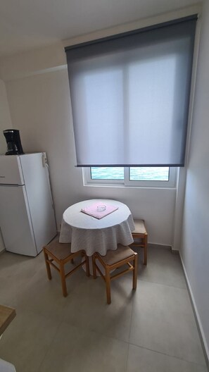 Cozy room with a small table and chairs, a refrigerator, and a coffee maker.