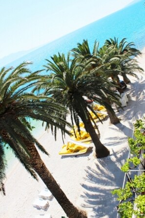 A beach with palm trees and a yellow chair. - Apartments Pansion Franka 4* - Apt 7 (Brist)