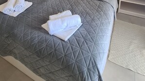 Habitación de hotel con cama, dos mesitas de noche, un espejo, un equipo de aire acondicionado, un sofá y una alfombra.