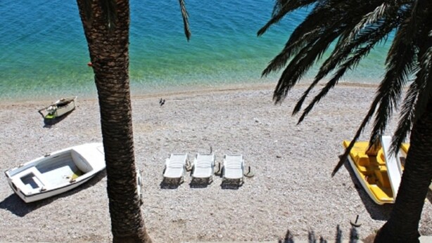 Una spiaggia con una fila di sedie a sdraio bianche, una piccola barca e una barca gialla sulla riva.