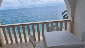 Un balcone con vista sul mare, un tavolo e due sedie.