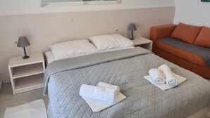 Una camera da letto con un letto grande, un comodino, una poltrona e uno specchio, con condizionatore d'aria a parete.