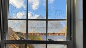 Una ventana con vista a una playa, palmeras y cielo despejado.