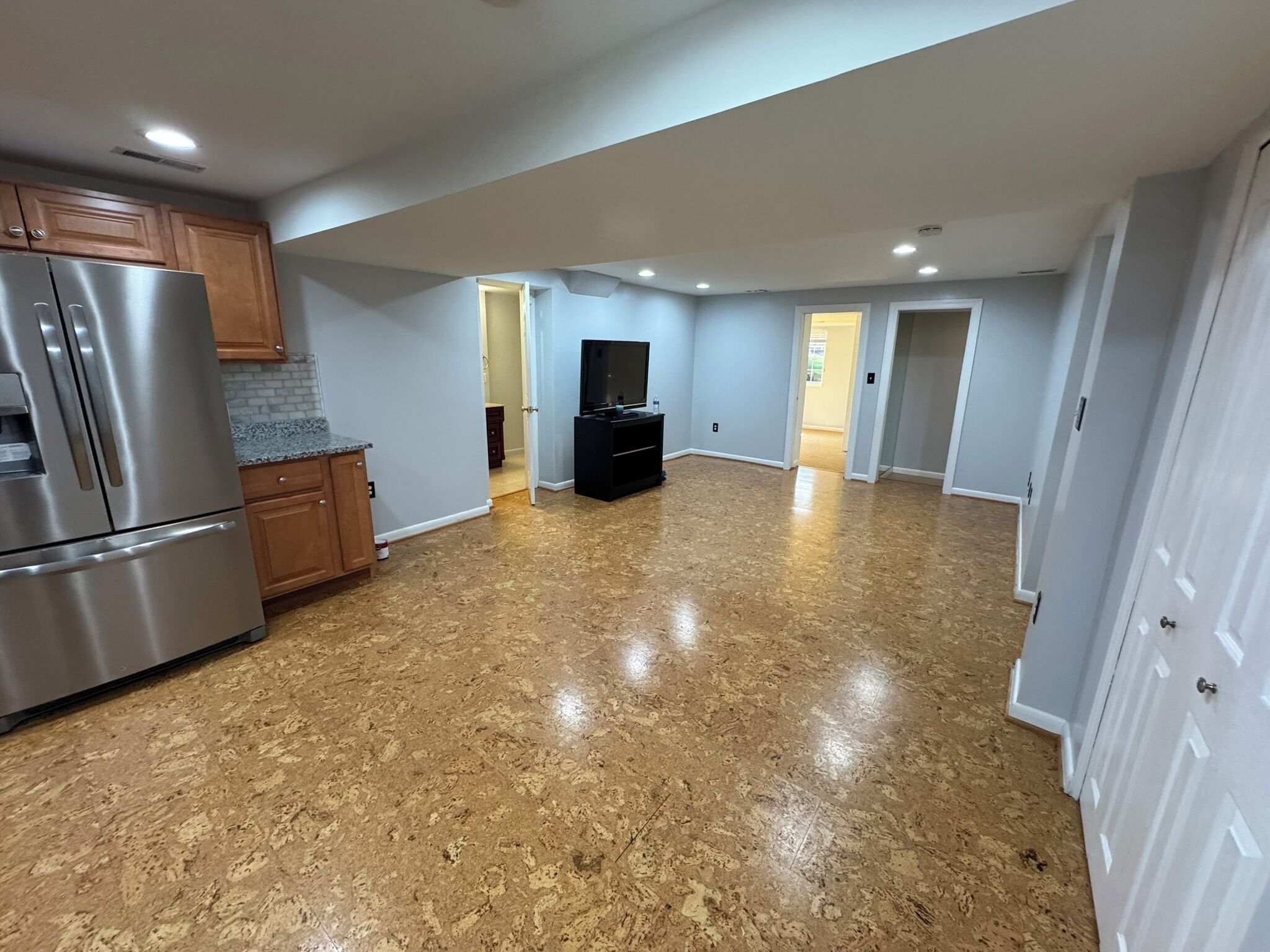 A spacious kitchen with a stainless steel refrigerator, wooden cabinets, and a granite countertop.