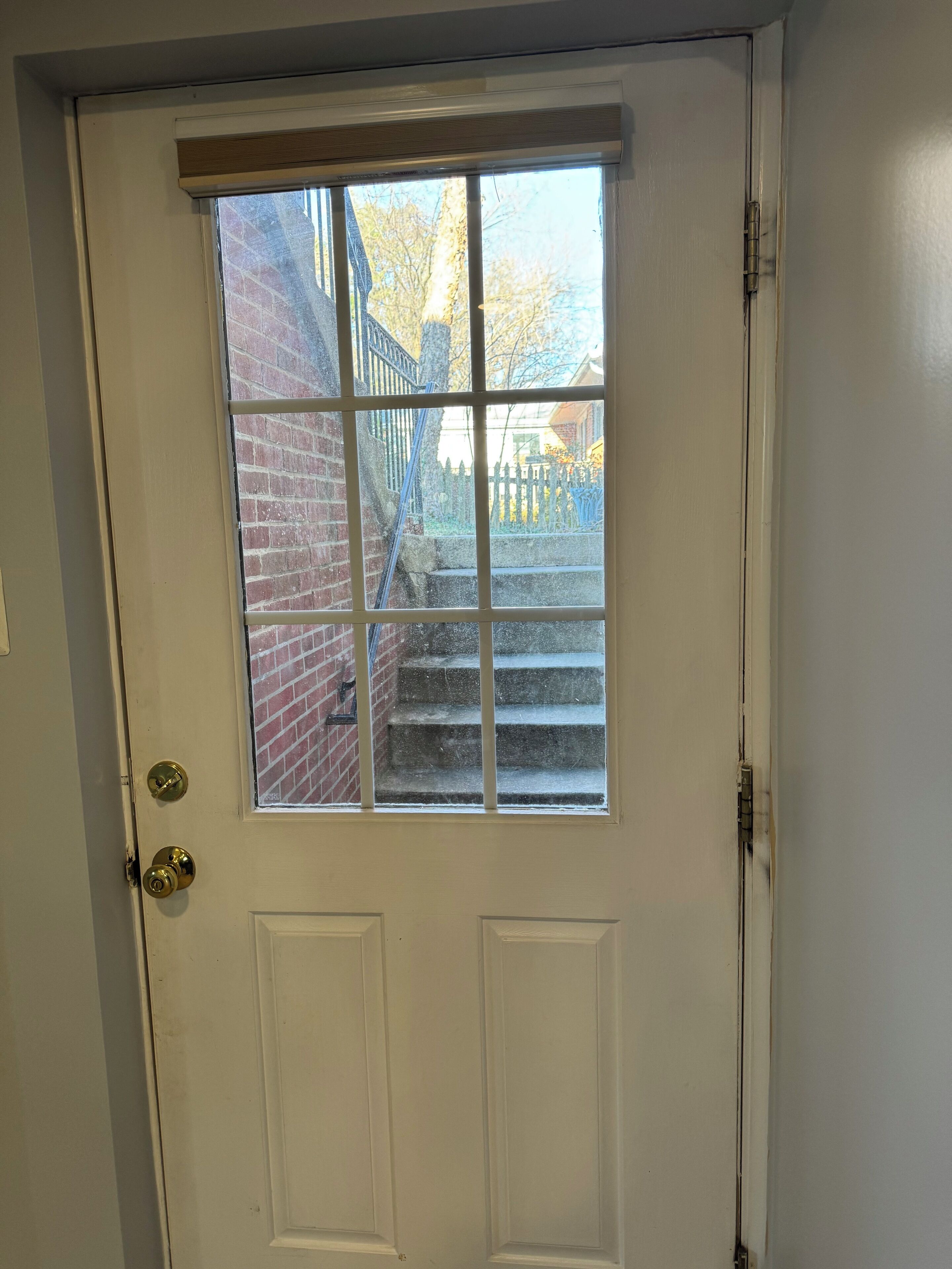 A white door with a window and a brass doorknob.