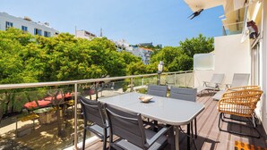 A balcony with a table and chairs, overlooking a pool and greenery. - Albufeira - Anna Town (Albufeira)