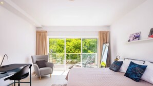A bedroom with a large bed, a desk, a chair, and a balcony with a view of greenery. - Albufeira - Anna Town (Albufeira)
