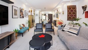 A modern living room with a sofa, two black chairs, a coffee table, and a TV. There are framed pictures on the walls and a rug on the floor. - Albufeira - Anna Town (Albufeira)