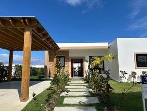 A modern house with a covered patio, a stone pathway, and a well-maintained garden. - Villa Tranquila: Luxury Villa in Sosua Ocean Village, Dominican Republic (Sosua)