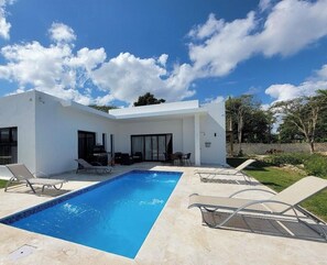 A modern house with a swimming pool, outdoor seating, and a garden. - Villa Tranquila: Luxury Villa in Sosua Ocean Village, Dominican Republic (Sosua)