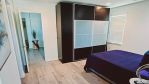 A bedroom with a bed, a wardrobe, a small table, and a potted plant. - 3Bedroom House in a family orientated neighborhood (Chula Vista)