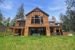 A two-story wooden house with a large front window, a covered porch, and a deck.