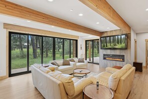 A modern living room with a fireplace, large windows, and a television. - Suncadia-luxury 4bd ensuite spa retreat & on-site EV charger on Prospector 13. A (Cle Elum)
