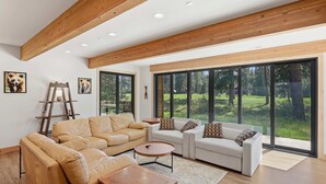 A spacious living room with a high ceiling, large windows, and a view of a green landscape. - Suncadia-luxury 4bd ensuite spa retreat & on-site EV charger on Prospector 13. A (Cle Elum)