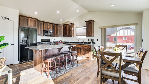Una cocina moderna con armarios de madera, una isla central con taburetes y un comedor con mesa y sillas.