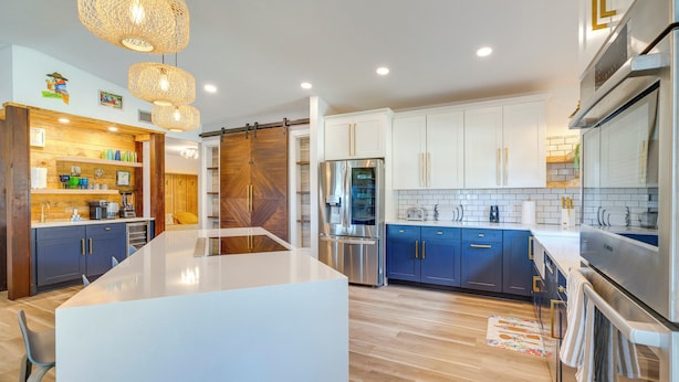 A modern kitchen with a central island, stainless steel appliances, and a wooden accent wall. - Canal-Front Gem w/ Hot Tub, Foosball in Cape Coral (Cape Coral)