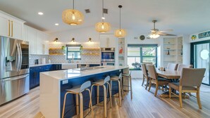 A modern kitchen with a large island, bar stools, and pendant lighting. - Canal-Front Gem w/ Hot Tub, Foosball in Cape Coral (Cape Coral)